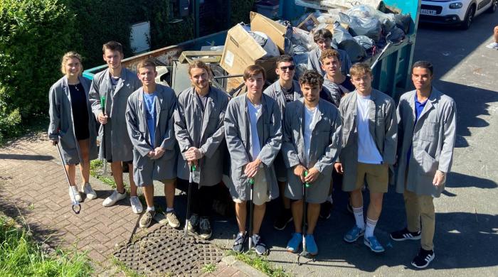 Etudiants devant une benne à déchets pendant l'action solidaire
